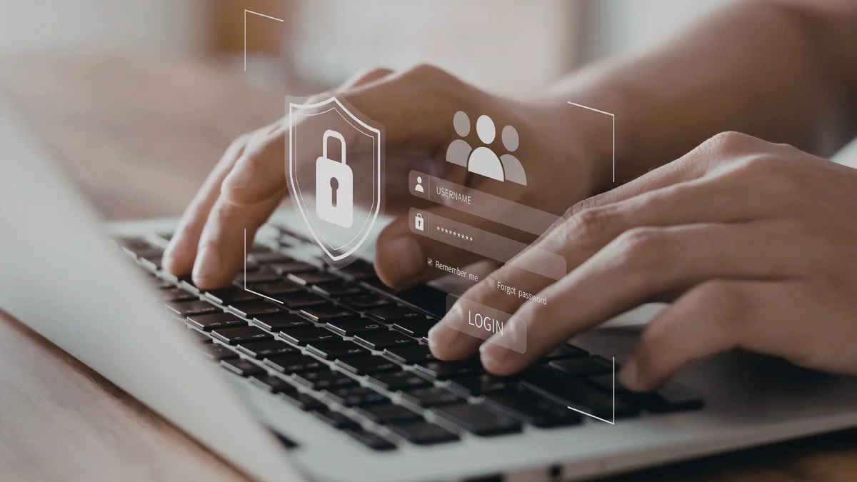 Hands typing on a laptop with digital security icons