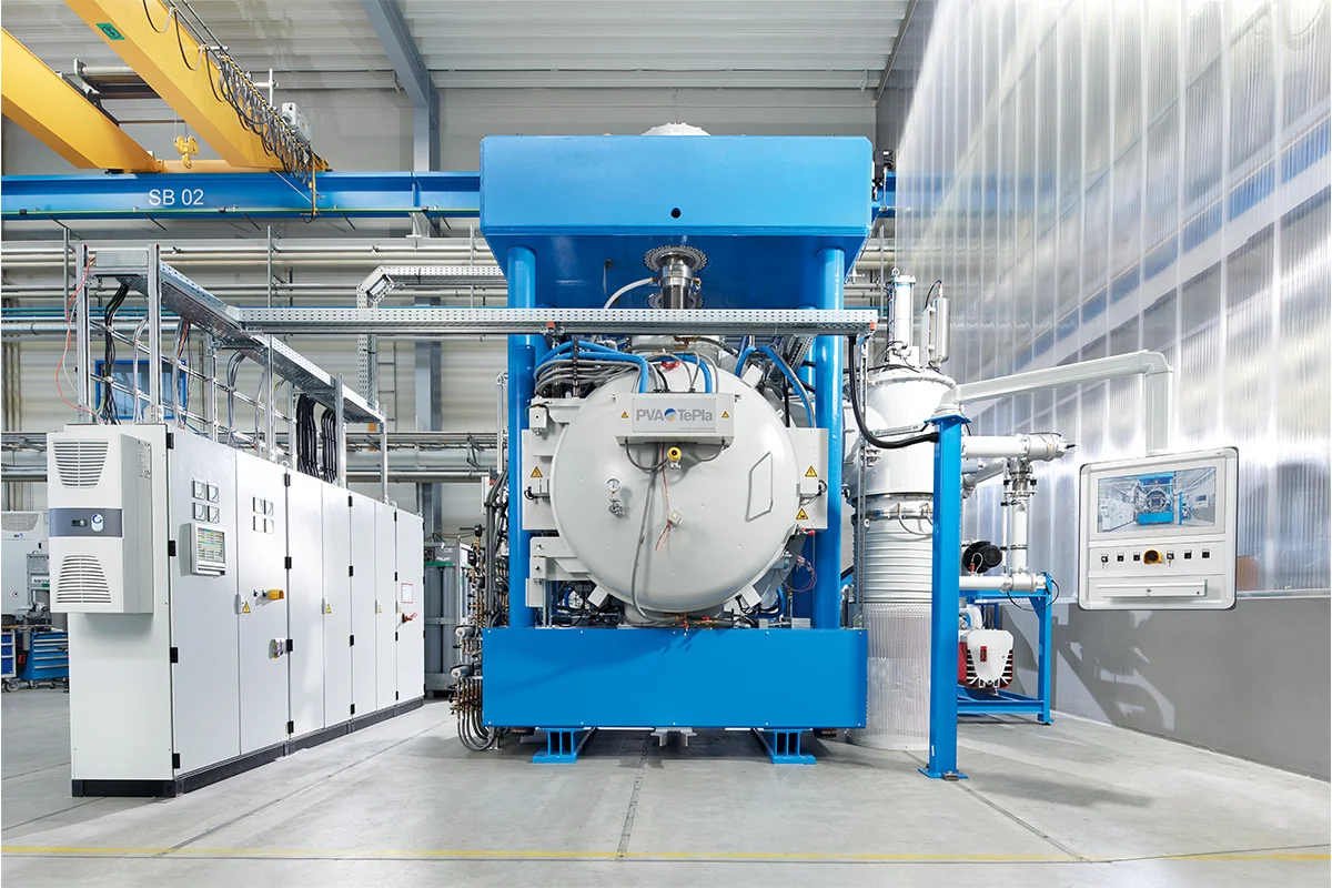Large industrial diffusion bonding system with blue frame and cylindrical vacuum chamber in a manufacturing facility.