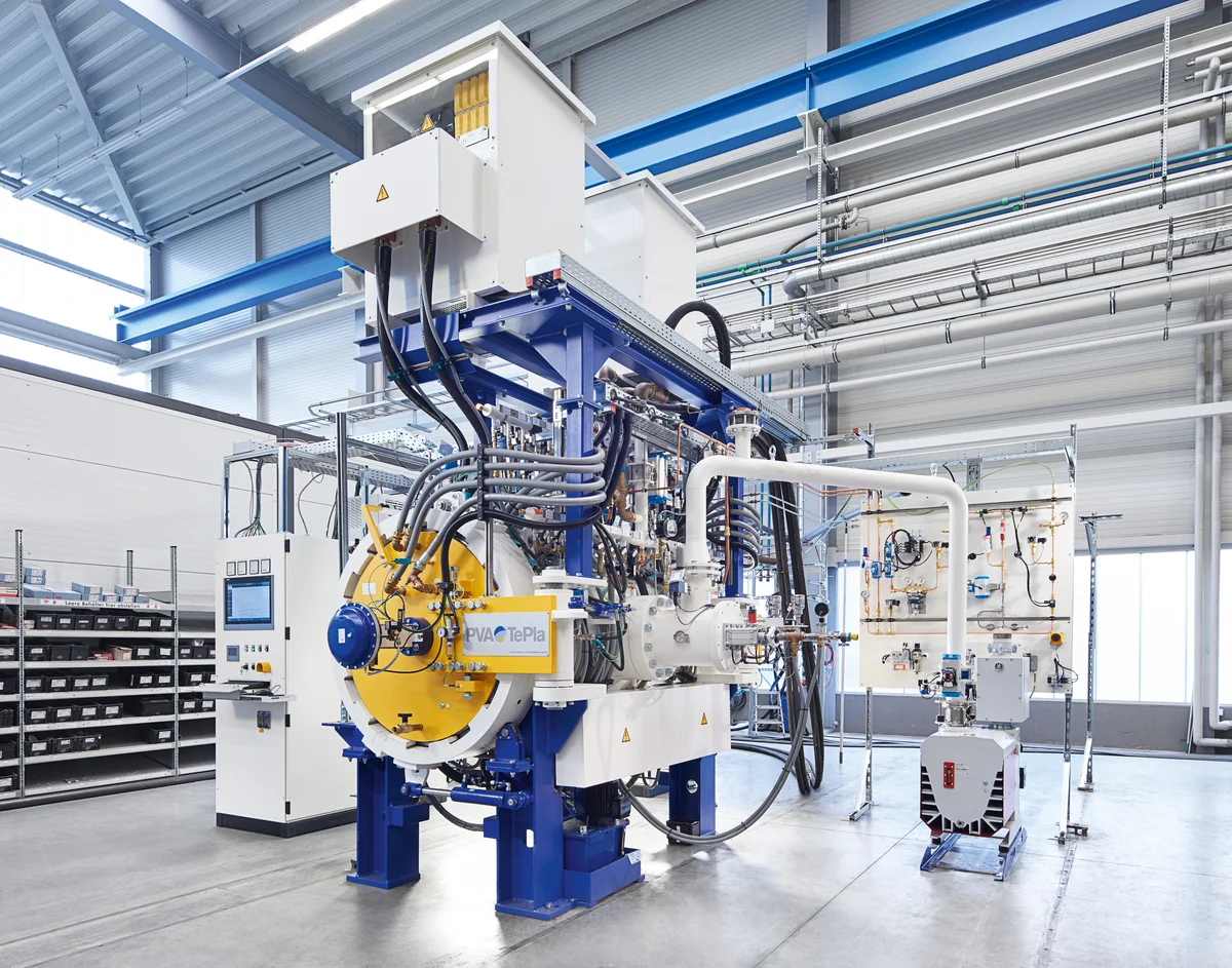 Large industrial hot-press system on a factory floor with multi-pillar structure and automated components.
