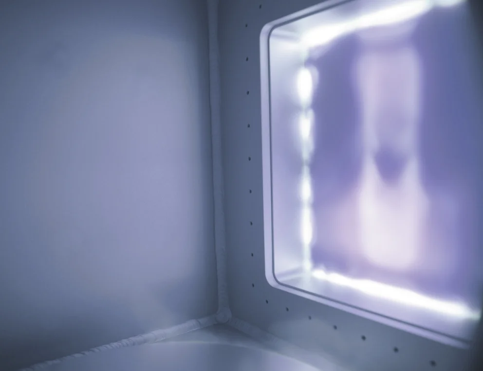 Interior view of an illuminated plasma chamber with glowing light and reflective walls.